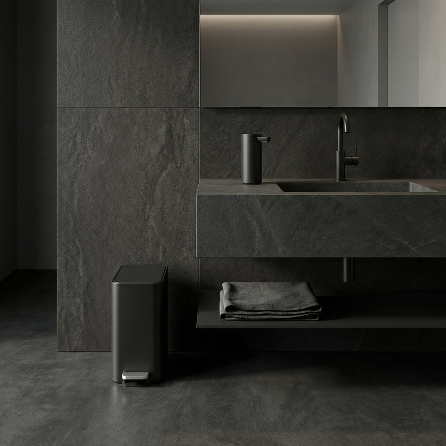 Simplehuman's 5L Slim Step Can in Matte Black in a modern, darker bathroom setting with black tiles and flooring complimented with the Simplehuman Sensor Pump in Matte Black. 
