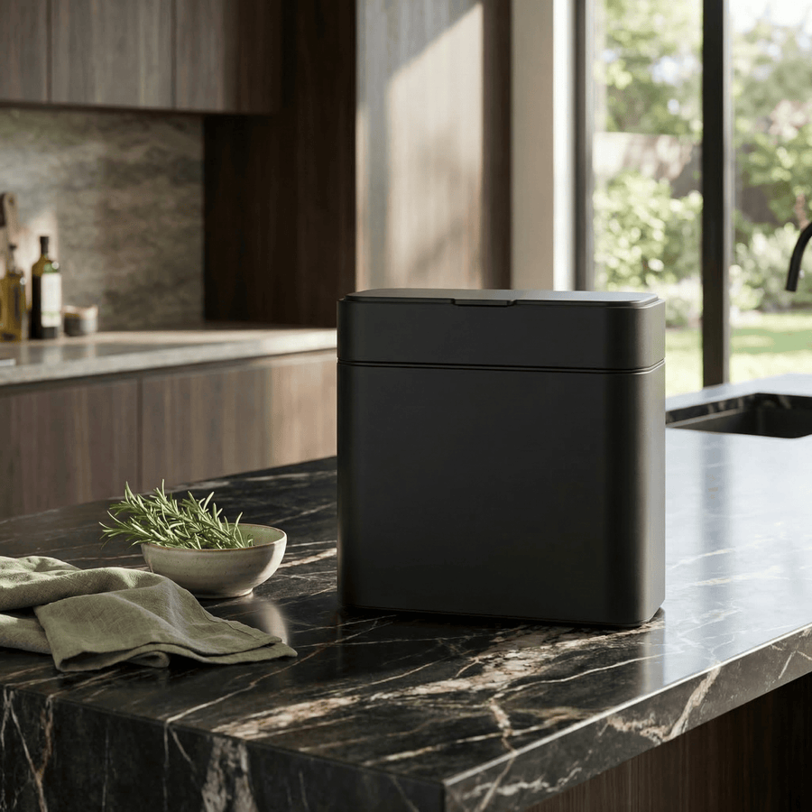 Simplehuman's Matte Black Compost Caddy in a modern kitchen countertop with black marble with bright lighting.